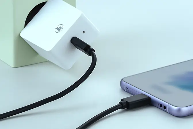 Un téléphone est en train d’être chargé sur une table.